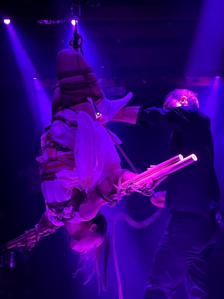 Artistic rope show by Louis Kordexe and Kiyome on stage with purple lighting during a Tokyo nightlife event.
